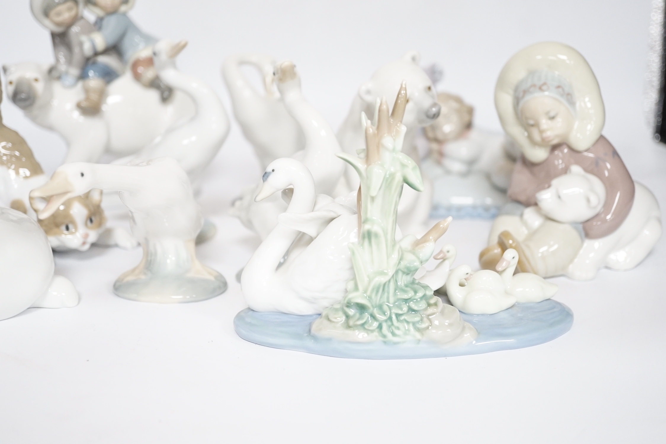 Eleven Lladro figure groups, including a collection of ducks, two Eskimo figure groups, a sleeping child with teddy on a cushion etc, none boxed